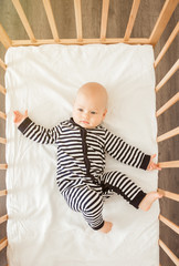 Newborn baby lying in bed in striped clothes