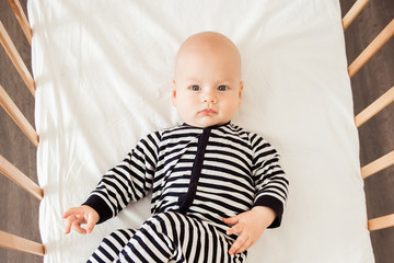 Newborn baby lying in bed in striped clothes
