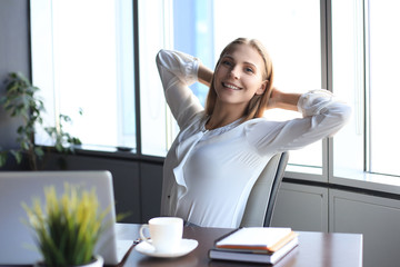 Business woman is relaxing with her hands behind her head and sitting on a chair in office