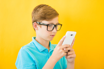 Handsome boy in glasses plays tablet. The concept of poor eyesight, harm of gadgets, myopia
