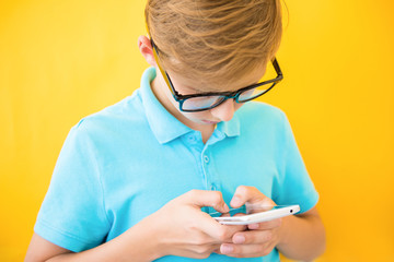 Handsome boy in glasses plays tablet. The concept of poor eyesight, harm of gadgets, myopia