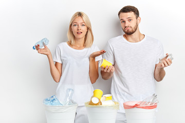 young woman and man with clueless expression shrugging their shoulders, close up portrait, isolated white background, studio shot