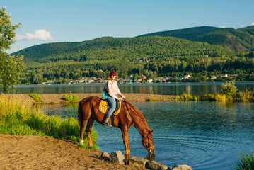 girl on a brown horse by the pond