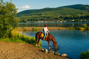 girl on a brown horse by the pond