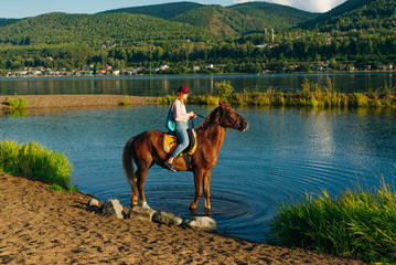 girl on a brown horse by the pond