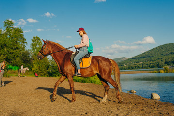 girl on a brown horse by the pond