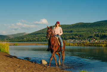 girl on a brown horse by the pond