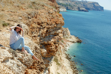 Fototapeta na wymiar Woman and beautiful landscape. A woman sits on a mountain overlooking the sea. 