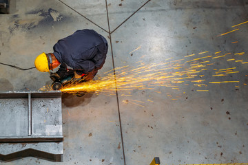 Male worker grinding spare part in metalworking workshop