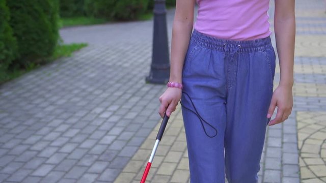 Young visually impaired asian woman with a cane is in the park close up slow mo