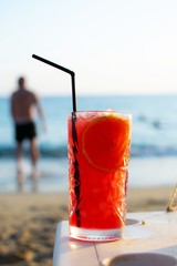 Zombie cocktail close up on the beach with nice soft background of a man entering in the sea.