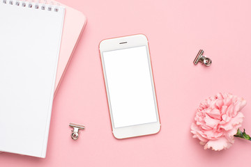 Mobile phone with pink carnation flower and notebook on a marble background