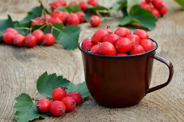 hawthorn berries in a mug on a wooden table close-up