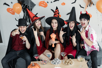 Gang of teen Asian  celebrate Halloween for sing a song and drink, dessert in the room.