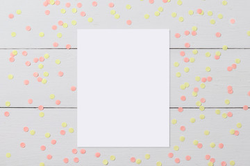 Mock-up of blank white card on light wooden background with confetti, funny desktop for any holiday