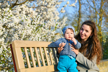 baby with mom rejoice in sunny weather. Charming mother with a small daughter in blue sat on the...