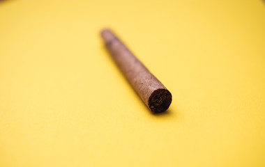 Einzelner Zigarrillo vor gelbem Hintergrund Unschärfe