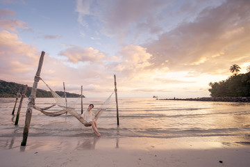 Woman relaxing in the hammock on tropical beach.