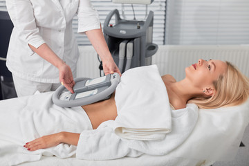 beautifil woman lying, having Cryolipolysis procedure in professional beauty clinic. close up side...