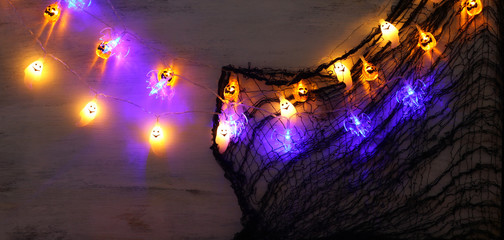 holidays concept of Halloween background with spider web and colorful garland lights