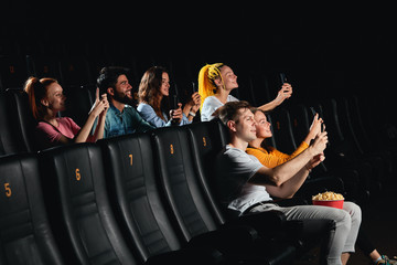 cheerful positive young people pirating movie with smartphones. side view photo.