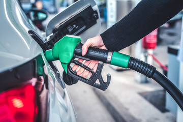 Woman pumping gasoline fuel in car at gas station. © Zedspider