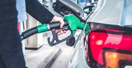 Woman pumping gasoline fuel in car at gas station. © Zedspider