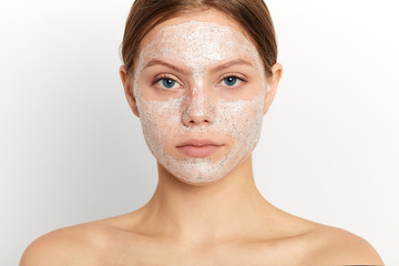 Portrait of relaxing shirtless beautiful woman with cream lotion on face standing over white background, studio shot. close up portrait