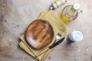 Wooden plate and yellow cotton napkin on beige background.