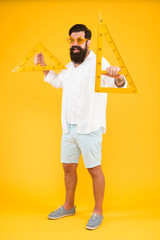Tools you need for your drawing. Geometry or technical drawing teacher. Bearded man holding drawing instruments on yellow background. Engineer using triangles for making engineering drawing