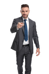 smiling young businessmam walking and pointing his finger