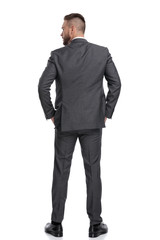 back view of  young businessman standing with hands in pockets