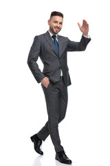 happy young businessman is walking and waving his hand