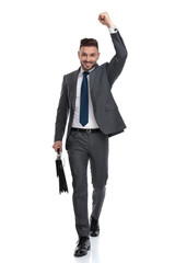 ecstatic young businessman walking with suitcase and celebrates success