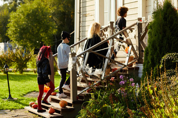 Side view at children trick or treating on Halloween, kids walking in row on stairs of decorated...