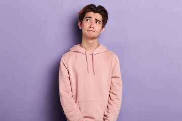 pensive puzzled thoughtful guy looking up, trying to remember something, close up photo. isolated blue background, studio shot. let me think