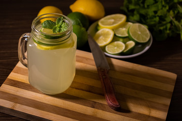 Lemonade with mint in a glass on a kitchen table.- Lemon and lime juice with mint leaves.