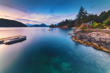 Brilliant sunset rocky beach scenes at sunset with mountains, sky and clouds lit up in early autumn.  Pacific North West Bowen Island British Columbia Canada close to Vancouver. © Jason