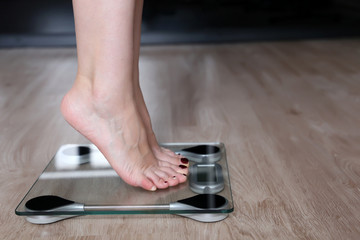 Slimming and diet, bare female feet on a scales. Woman measuring her weight at home standing on tiptoe, weight loss concept