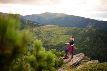 girl walks in the mountains with trekking poles