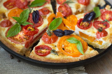Tomato tart made with shortcrust  pastry, red and yellow tomatoes, cheese and cream. Concept of healthy eating or vegetarian food on rustic wooden background