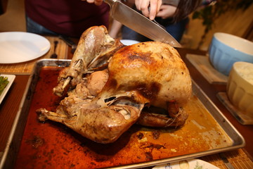 A pair of hands with a knife cuts a roasted tasty turkey with apples for Thanksgiving or Christmas