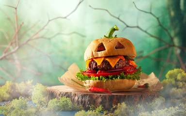 Halloween party burger in shape of scary pumpkin   on natural wooden board. Halloween food concept. - obrazy, fototapety, plakaty