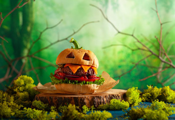 Halloween party burger in shape of scary pumpkin  on  wooden board. Halloween food concept.