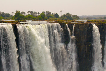 The Victoria Falls are a wide waterfall of the Zambezi River between the border towns of Victoria Falls in Zimbabwe and Livingstone in Zambia.