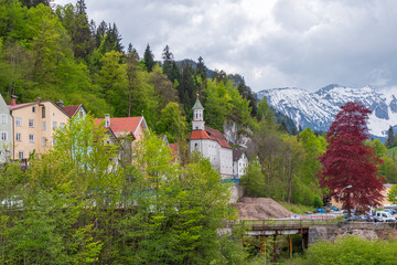 Fototapeta na wymiar View from the bridge of the outskirts of cozy Füssen against the backdrop of the Alps on a gloomy May morning