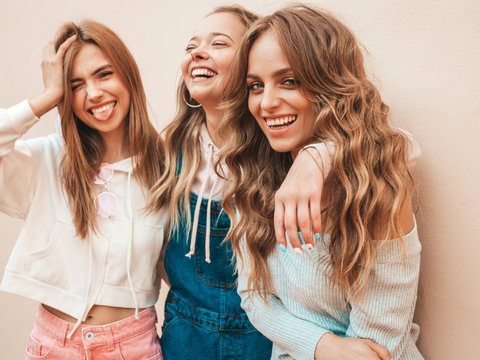 Portrait of three young beautiful smiling hipster girls in trendy summer clothes. Sexy carefree women posing on the street near wall.Positive models having fun.Hugging