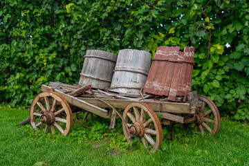 Fototapeta na wymiar alter hölzerner Wagen mit 3 Wasserbottichen auf Rädern im Freien