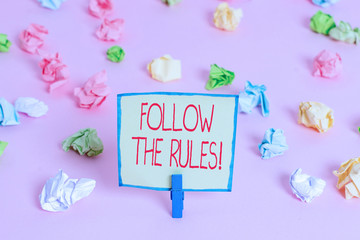 Text sign showing Follow The Rules. Business photo text go with regulations governing conduct or procedure Colored crumpled papers empty reminder pink floor background clothespin