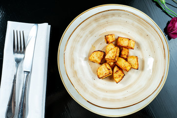 Delicate baked potato slices in a light bowl on a black background. Restaurant serving dishes. Home cooking. Food photo background for recipe or menu. Vegan food